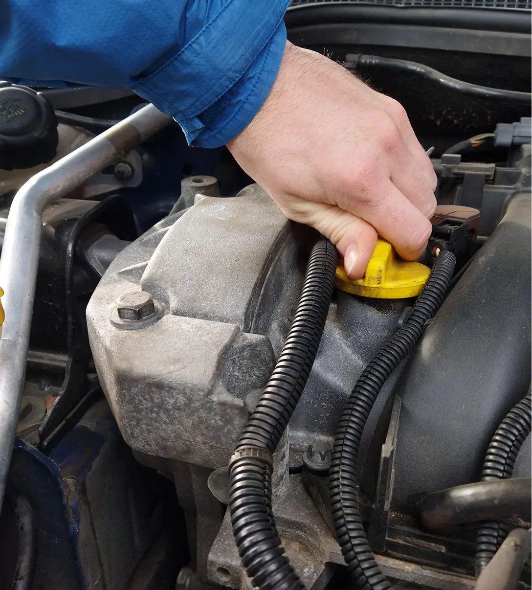 Hand checking engine oil dipstick in car.