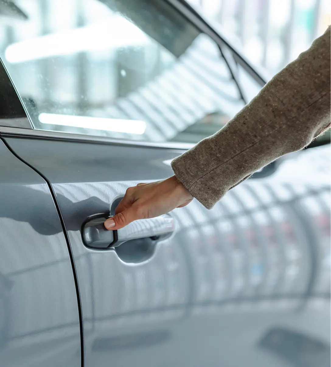 Hand opening car door in garage.